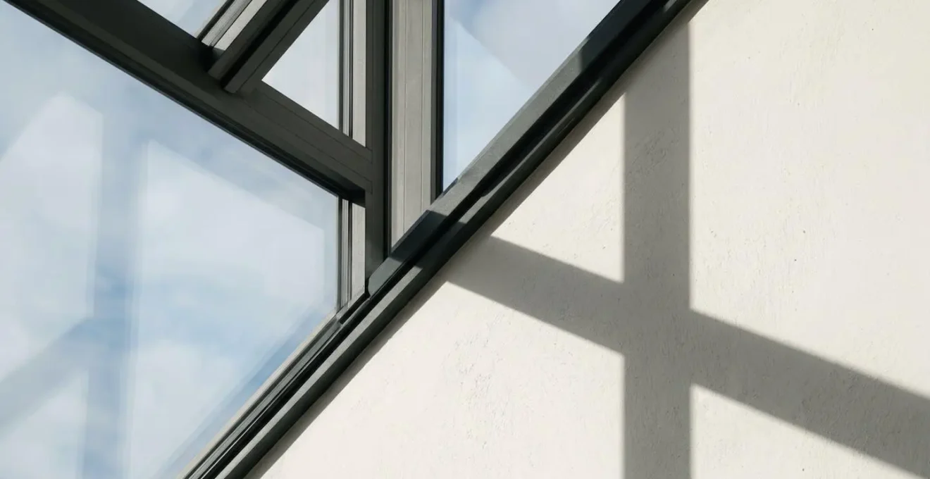 Détail architectural d'une fenêtre contemporaine avec projection d'ombres géométriques sur mur blanc